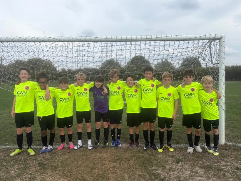 A youth football team in CWM Complete Waste Management shirts, standing in front of a goal.