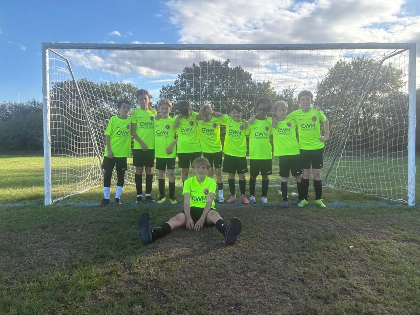 The Byron Red Star FC Under 11s team in CWM Complete Waste Management shirts, in front of a goal.