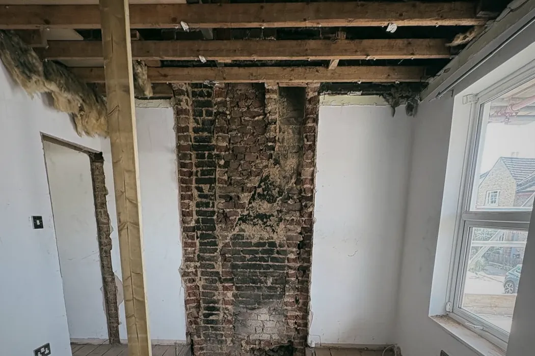 A room soft stripped back to the ceiling joists, the brick chimney breast and the floorboards