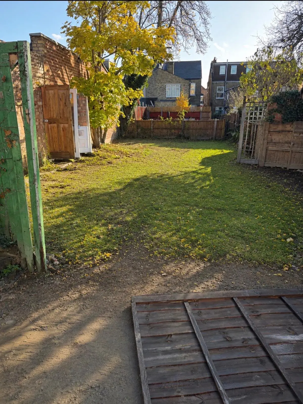After. Garden cleared and cut, the fence panels stacked flat and the ground clear.