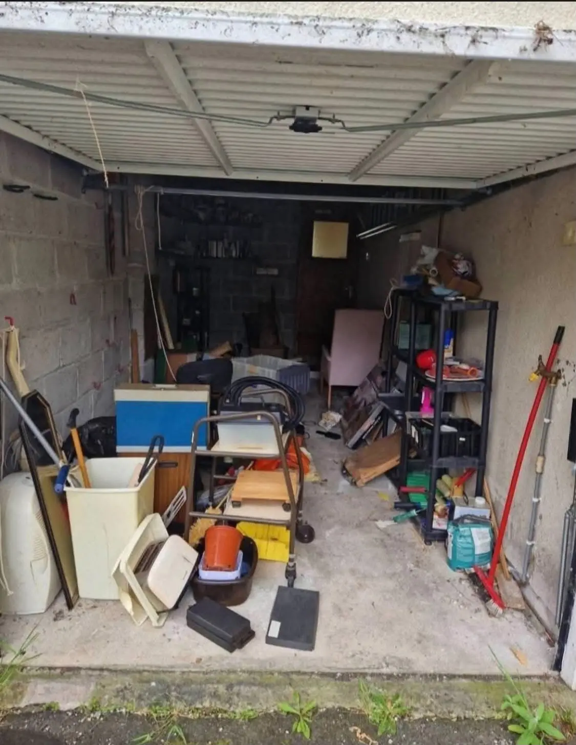 Before. Tools, timber, boxes and a mower filling the garage front to back.