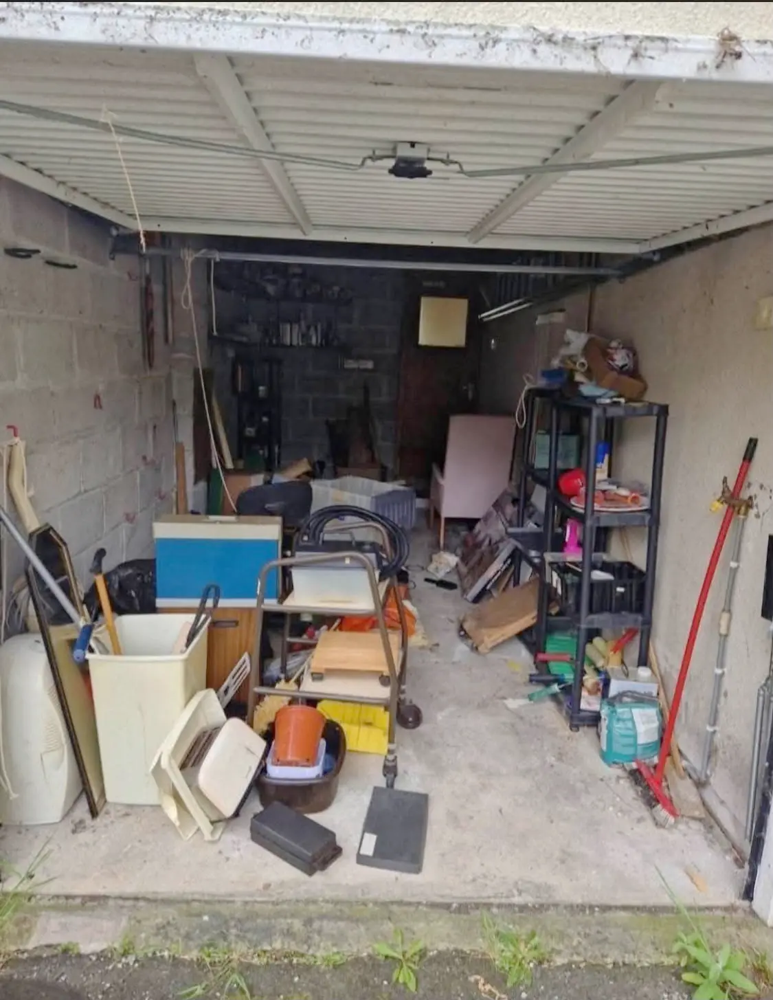Before. Tools, timber, boxes and a mower filling the garage front to back.