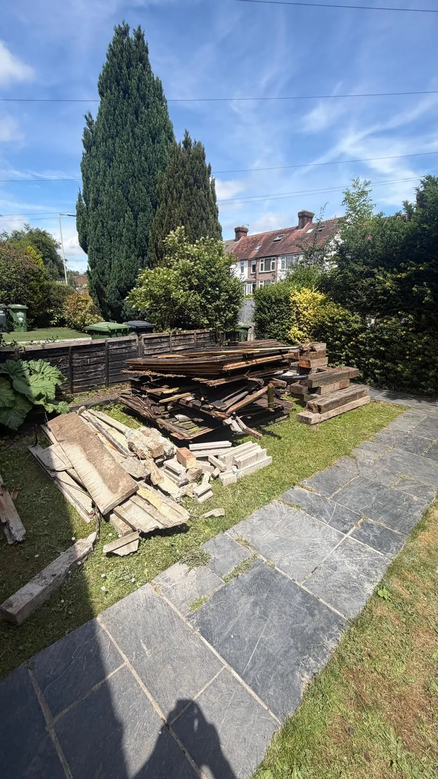 Before. A long pile of scrap timber stacked over the lawn and the slate path.