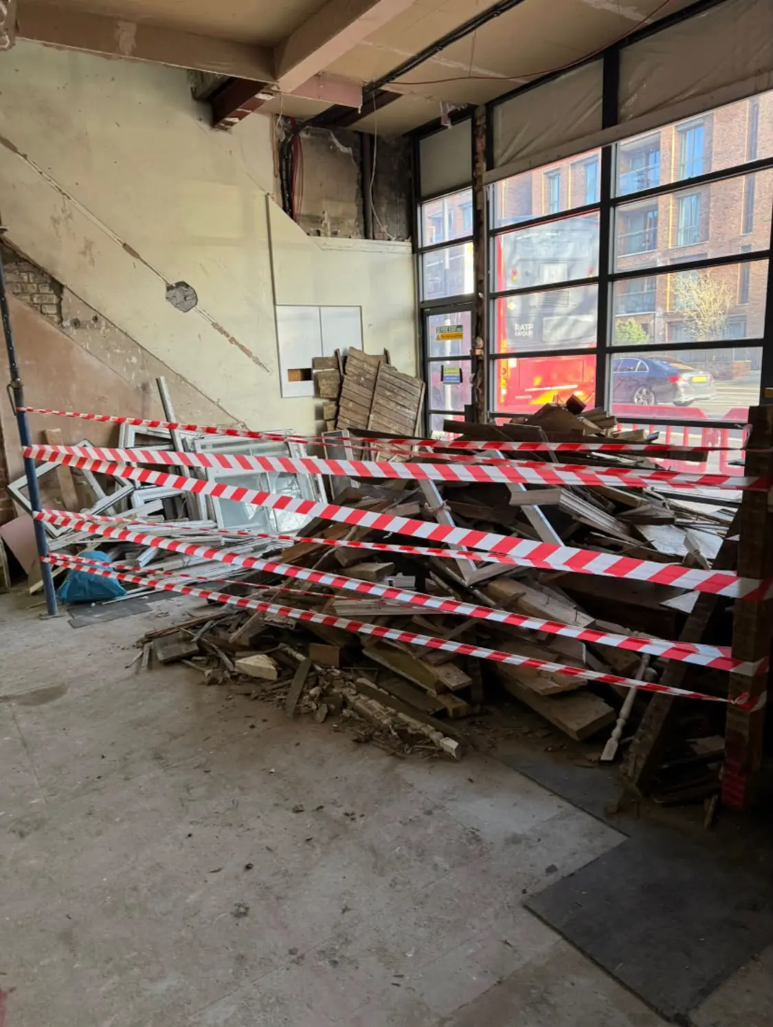Before. Broken pallets and timber piled behind hazard tape across the unit floor.