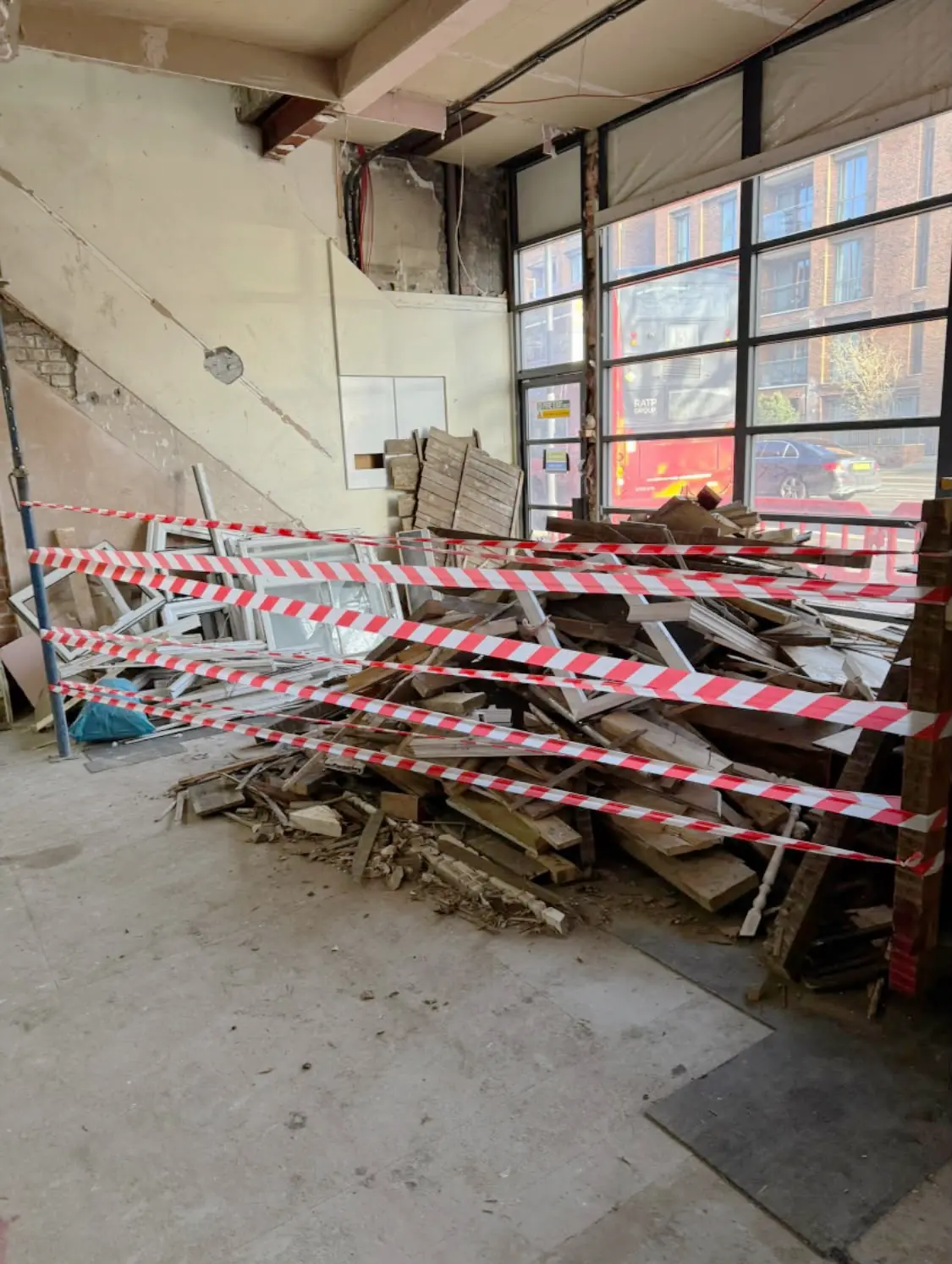 Before. Broken pallets and timber piled behind hazard tape across the unit floor.