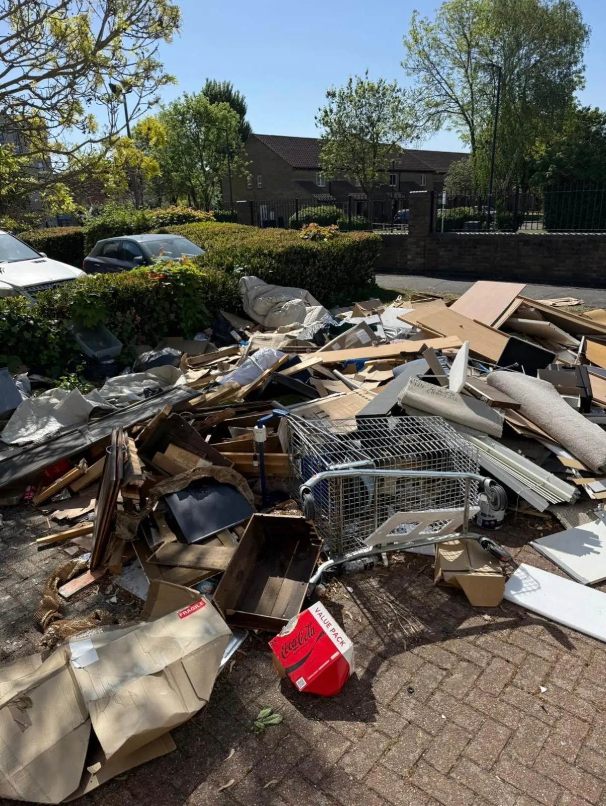 Before. Broken furniture, cardboard, a wire trolley and a fuel can dumped across the parking bay.
