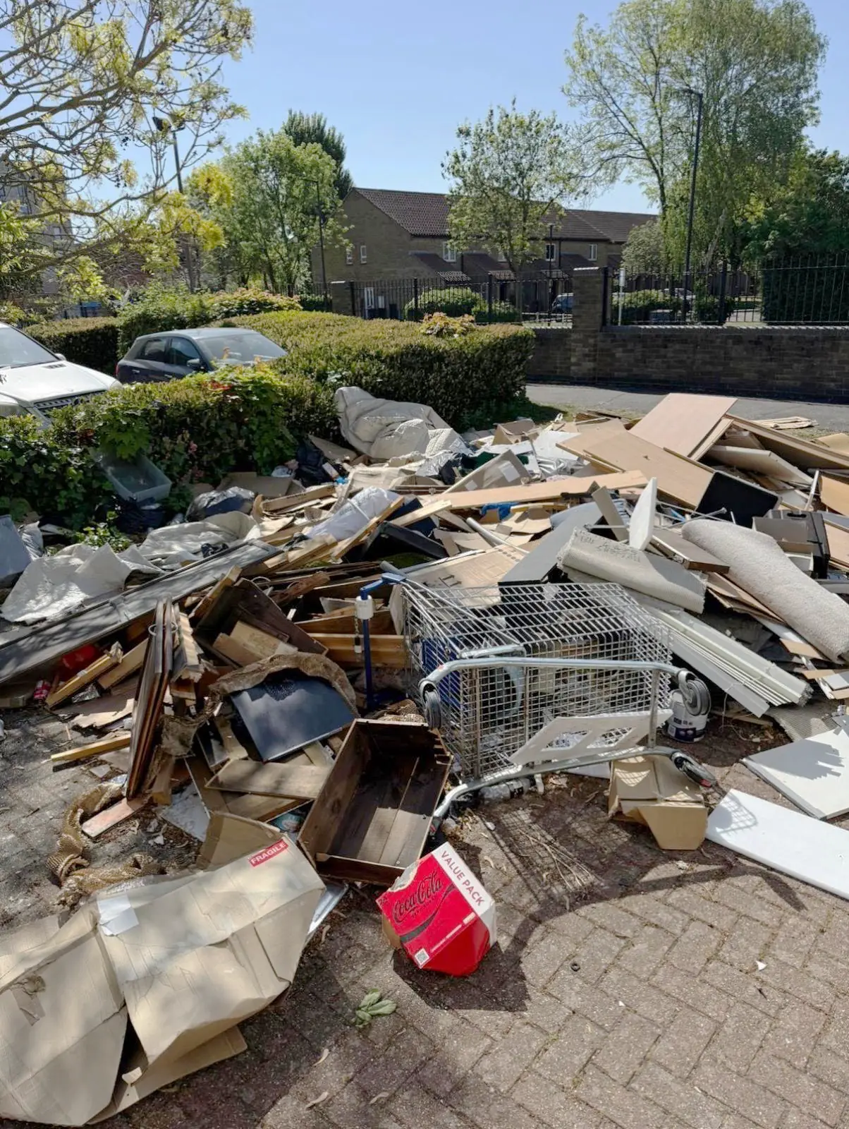 Before. Broken furniture, cardboard, a wire trolley and a fuel can dumped across the parking bay.
