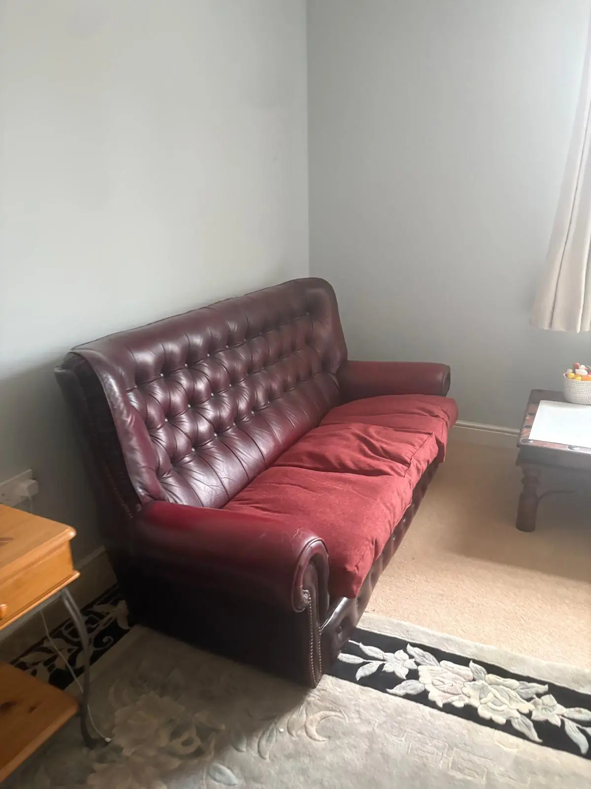 Before. A leather chesterfield and side furniture still in place on the rug.