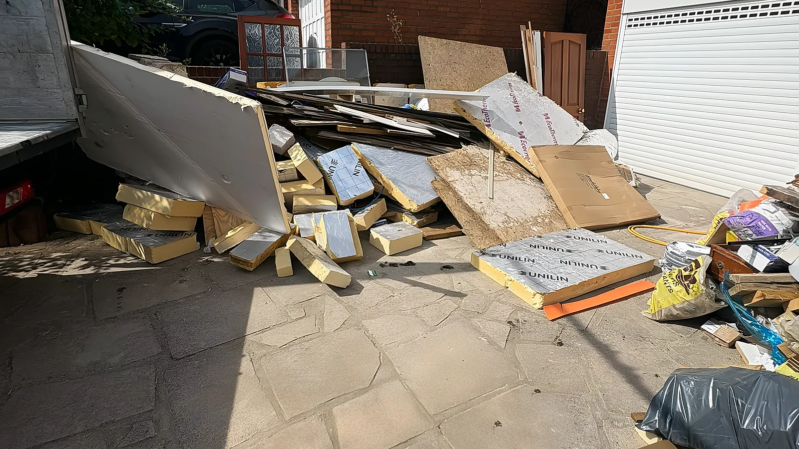 A side passage piled with plasterboard, timber and cardboard