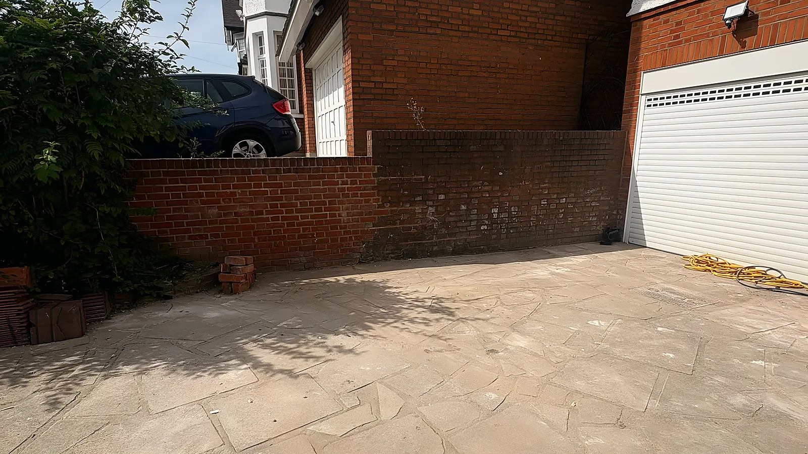 A patio and side passage swept clean, brick wall and garage door