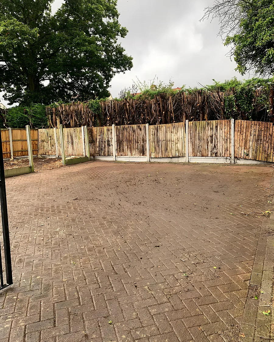 A block-paved yard swept clear, a new close-board fence and the hedge behind