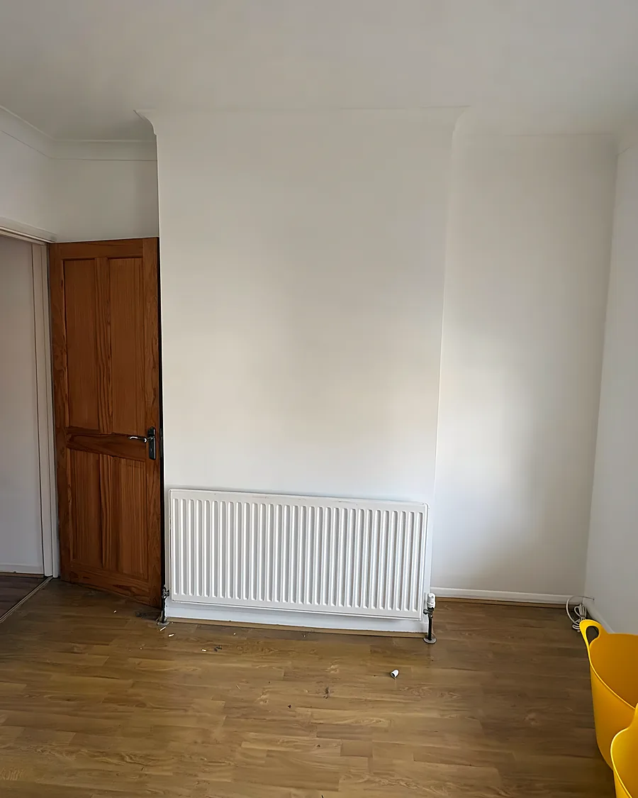 An empty room after a clearance, bare boards, a radiator and a pine door