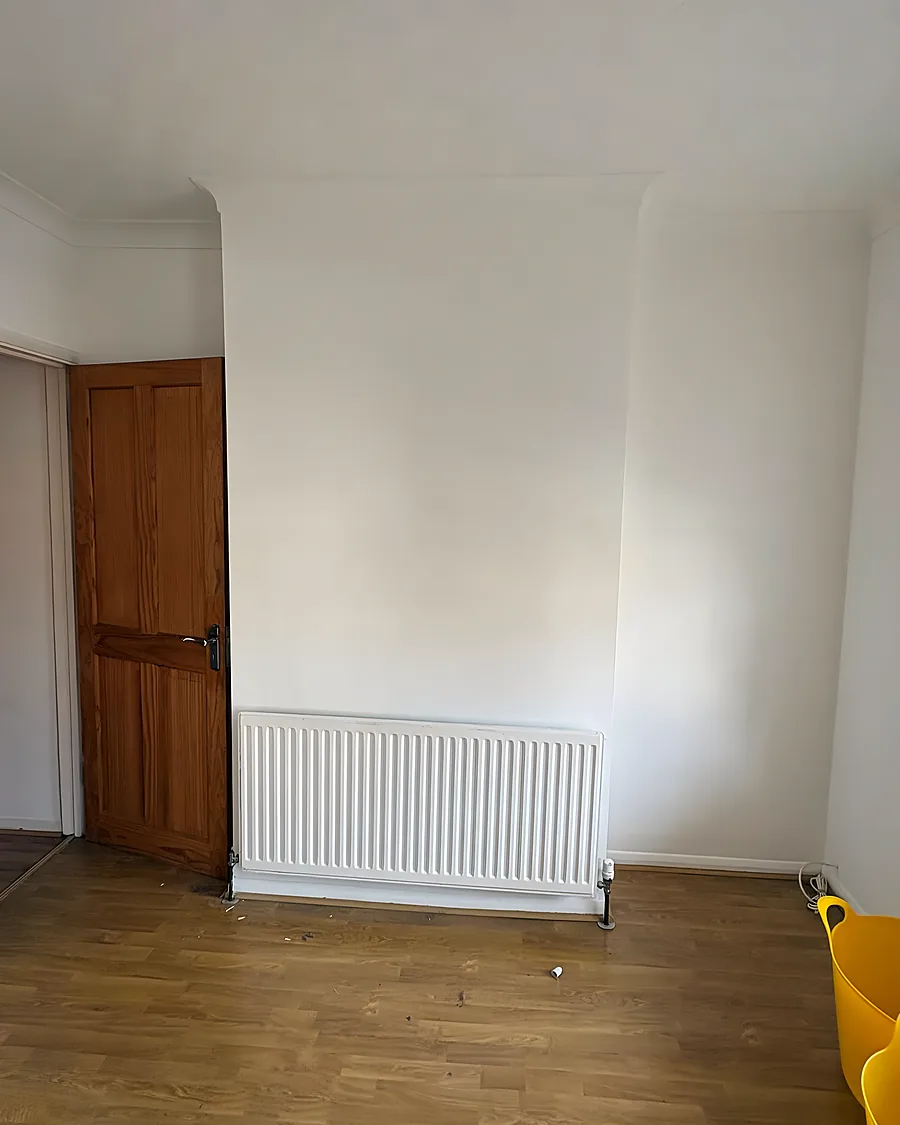 An empty room after a clearance, bare boards, a radiator and a pine door