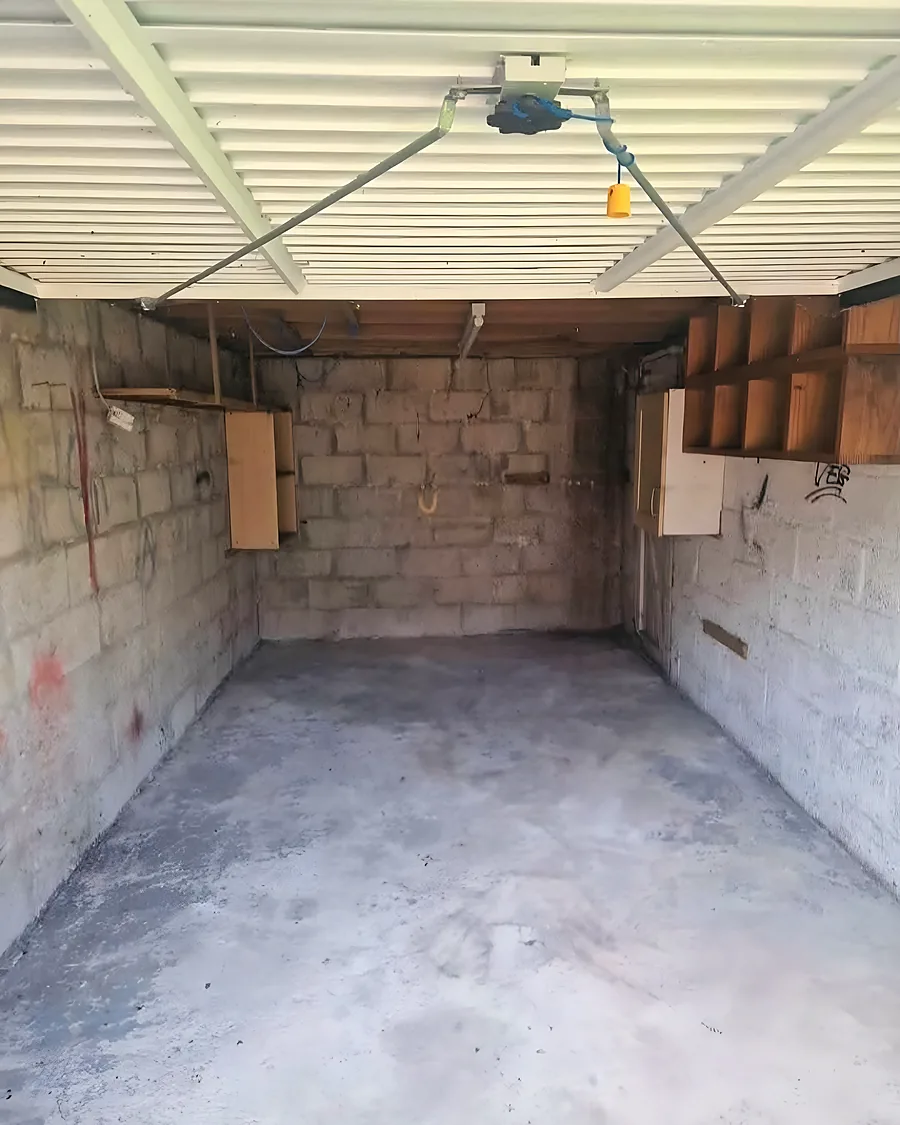 An emptied garage, swept concrete floor and bare block walls