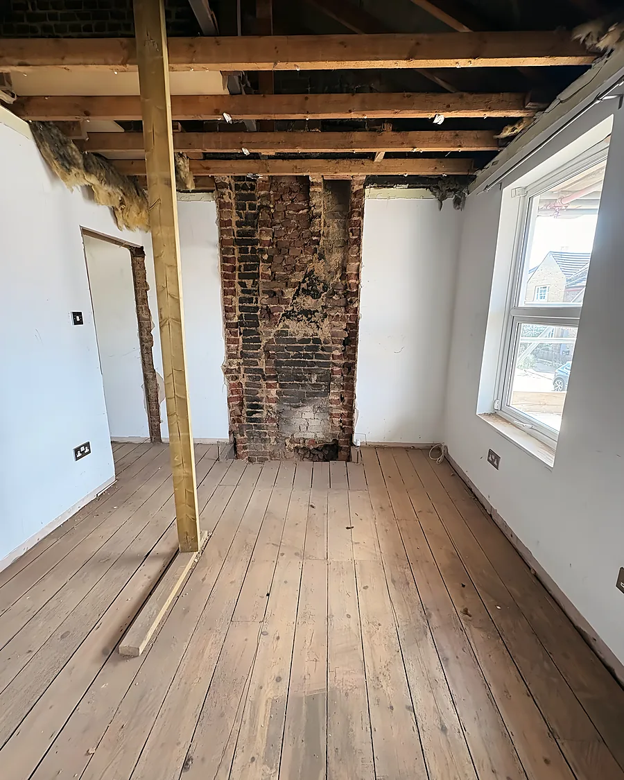 A room soft stripped back to the ceiling joists, the brick chimney breast and the floorboards