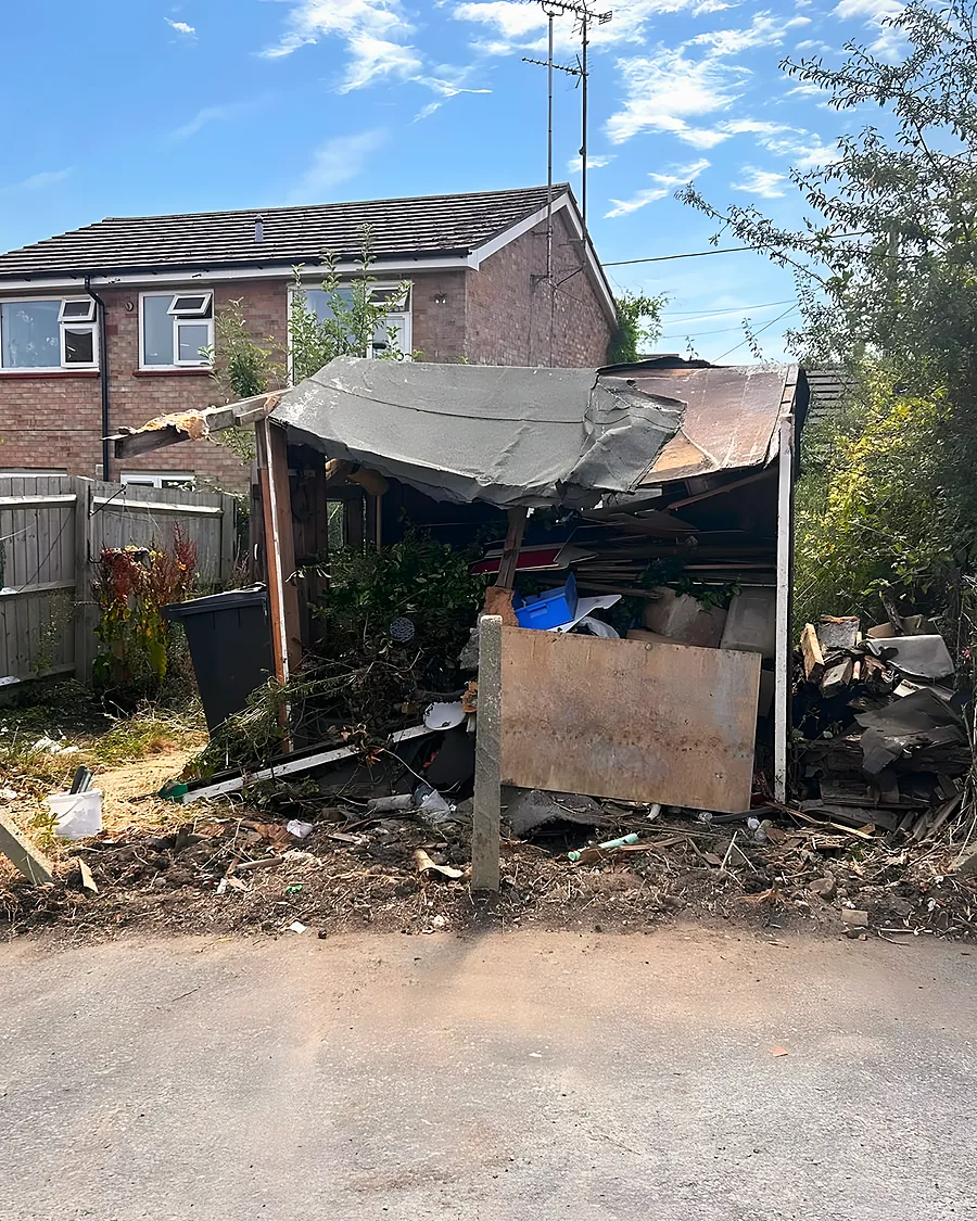A collapsed outbuilding between two fences, its roof caved in