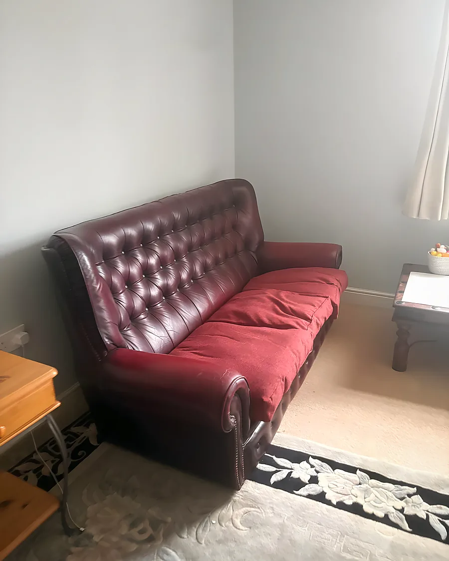 Before: A leather chesterfield and side furniture still in place on the rug.